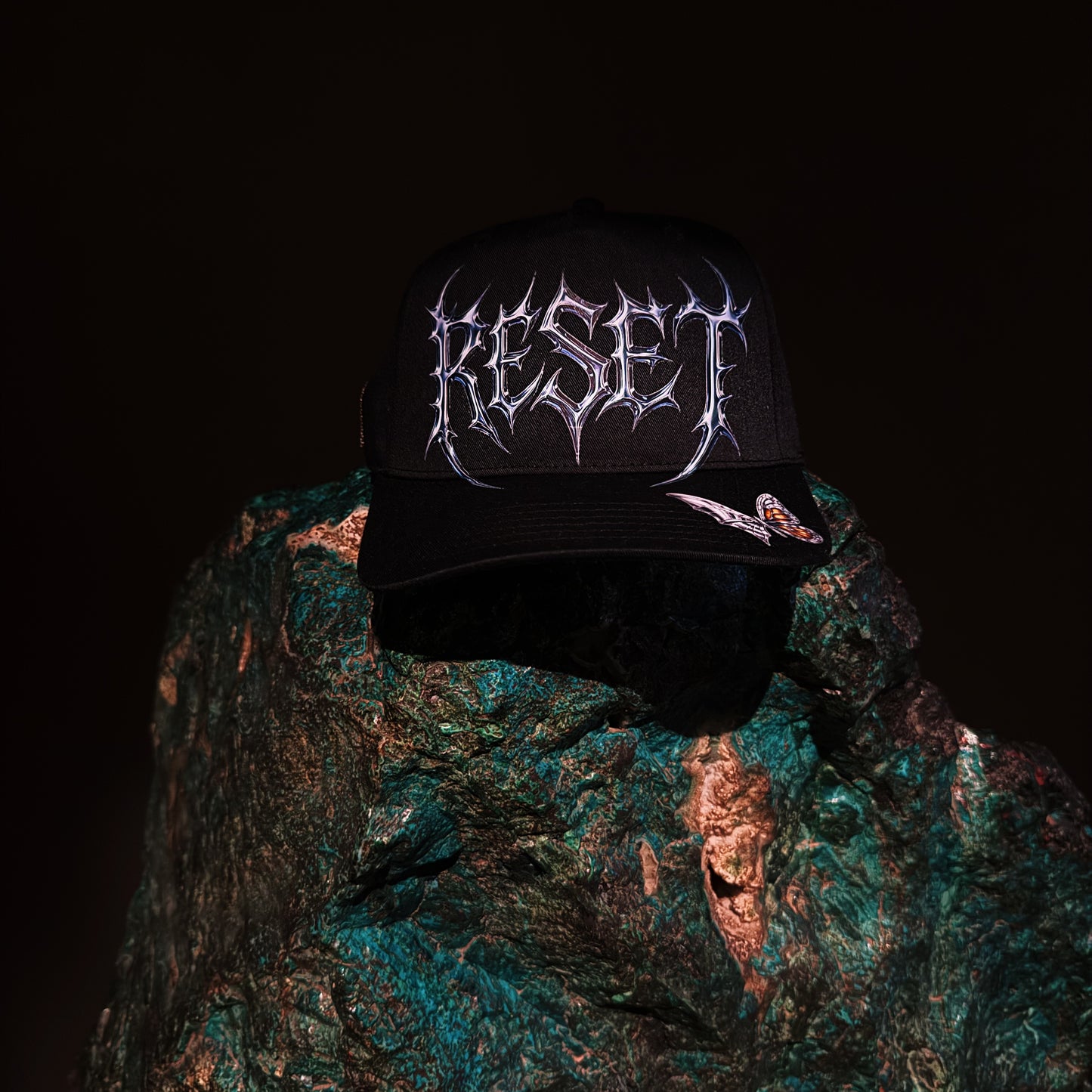 Black cap with 'RESET' logo on a textured green surface