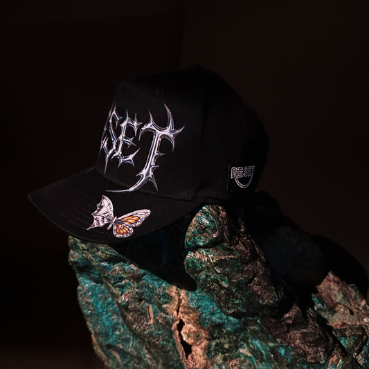 Black cap with white designs held over a textured surface