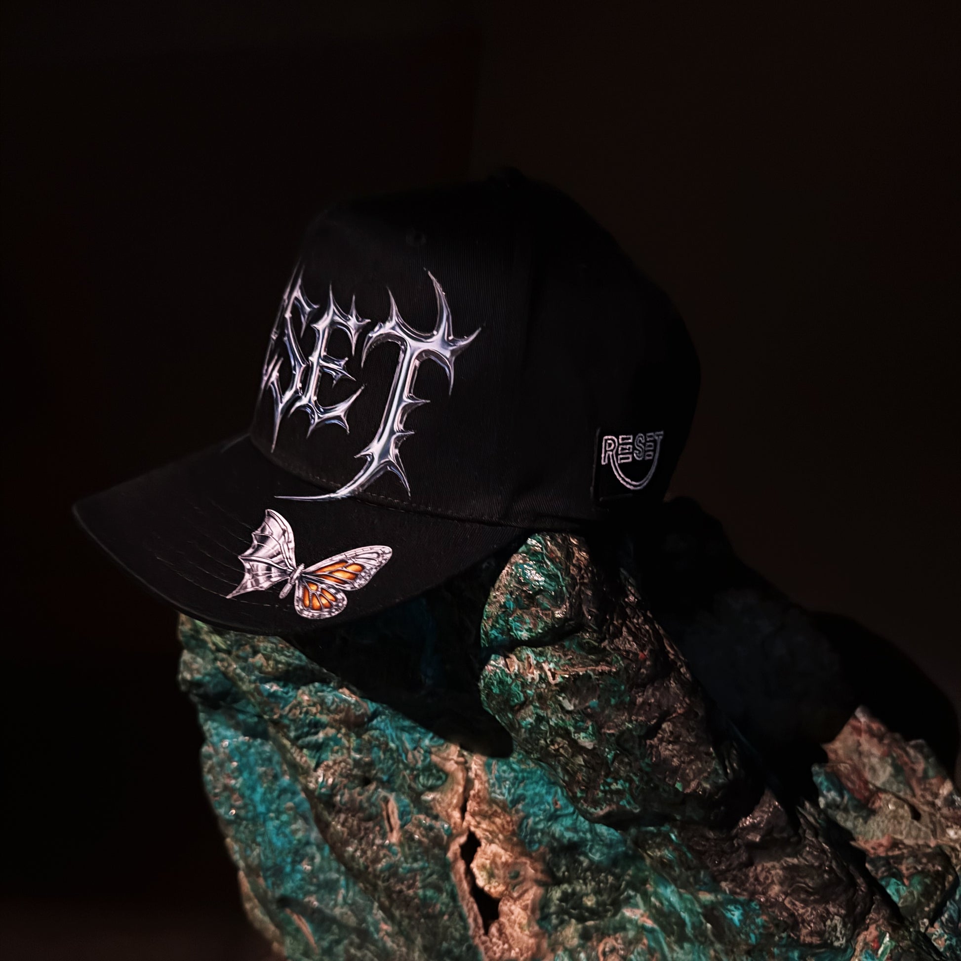 Black cap with white designs held over a textured surface